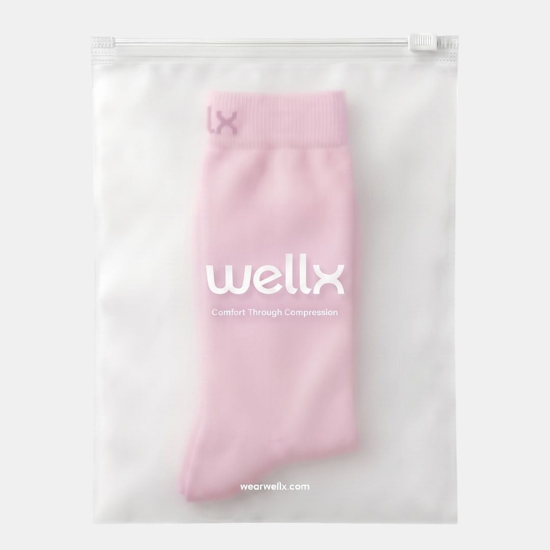 Candy Heart Pink Compression Socks For Women, A light pink compression sock inside a clear, zippered plastic storage pouch with the brand name 'wellx' printed on the front.