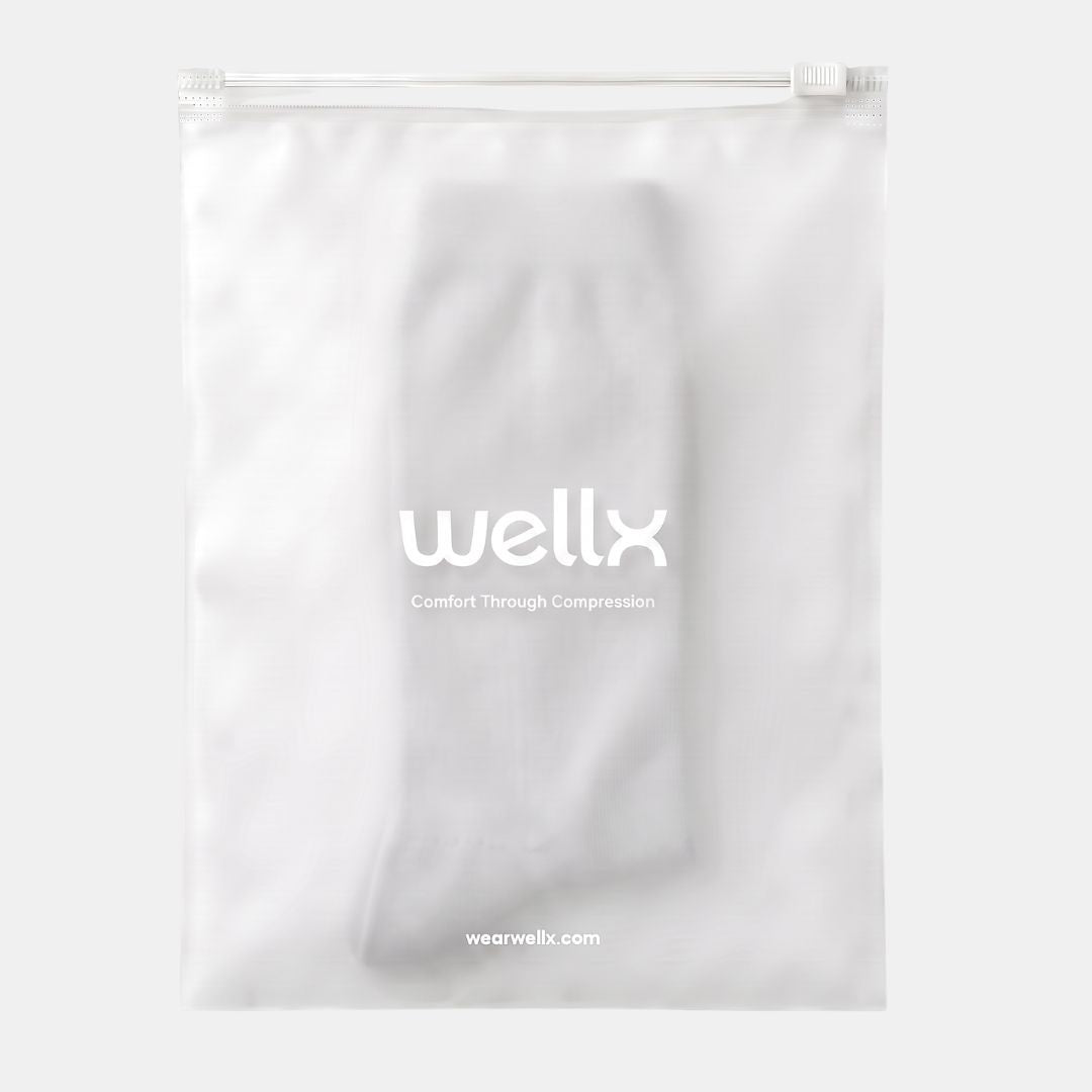 Light Grey Wide Calf Compression Socks For Men. A white compression sleeve inside a clear resealable plastic bag with the brand name 'wellx' printed in white on the front, set against a light gray background.