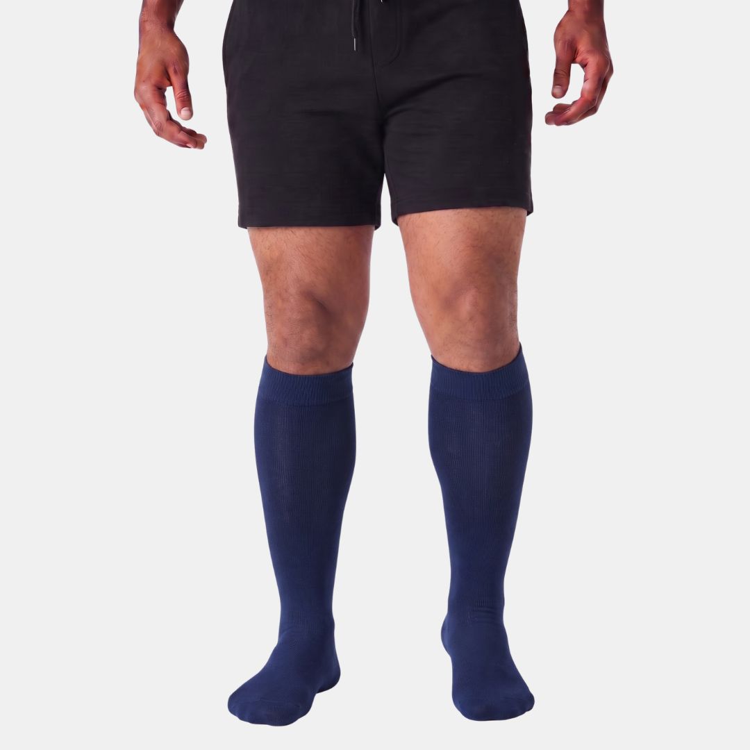 Navy Blue Wide Calf Compression Socks. A model from the waist down wearing black athletic shorts and navy blue knee-high compression socks against a light gray background.