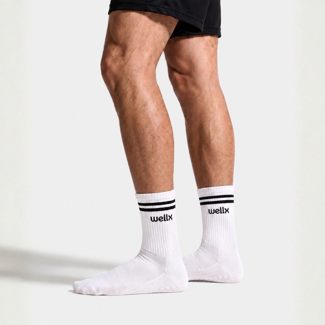 White Balance Grip Socks For Men with black double-stripe cuff and non-slip grip sole, worn standing with black athletic shorts, side profile