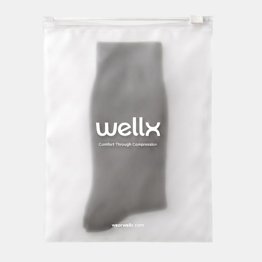 Black Wide Calf Compression Socks For Men. A gray compression sock inside a clear, zip-top plastic bag with the brand name 'wellx' printed in white on the front, set against a light gray background.
