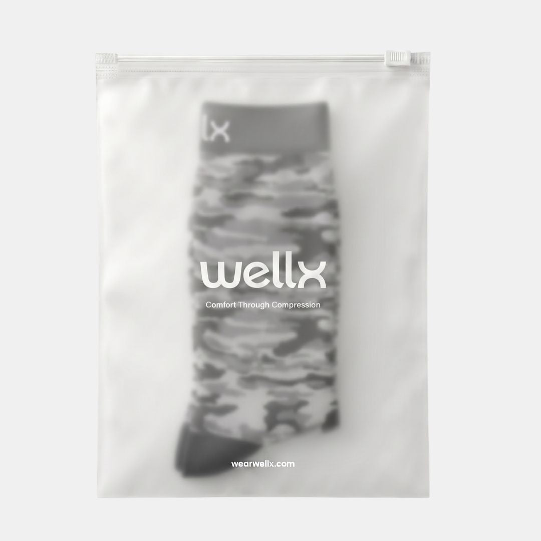 Stars Black Camouflage Compression Socks For Men, A single sock in a clear resealable pouch with branding and the text 'wellx Comfort Through Compression' printed on the front, shown against a light gray background.