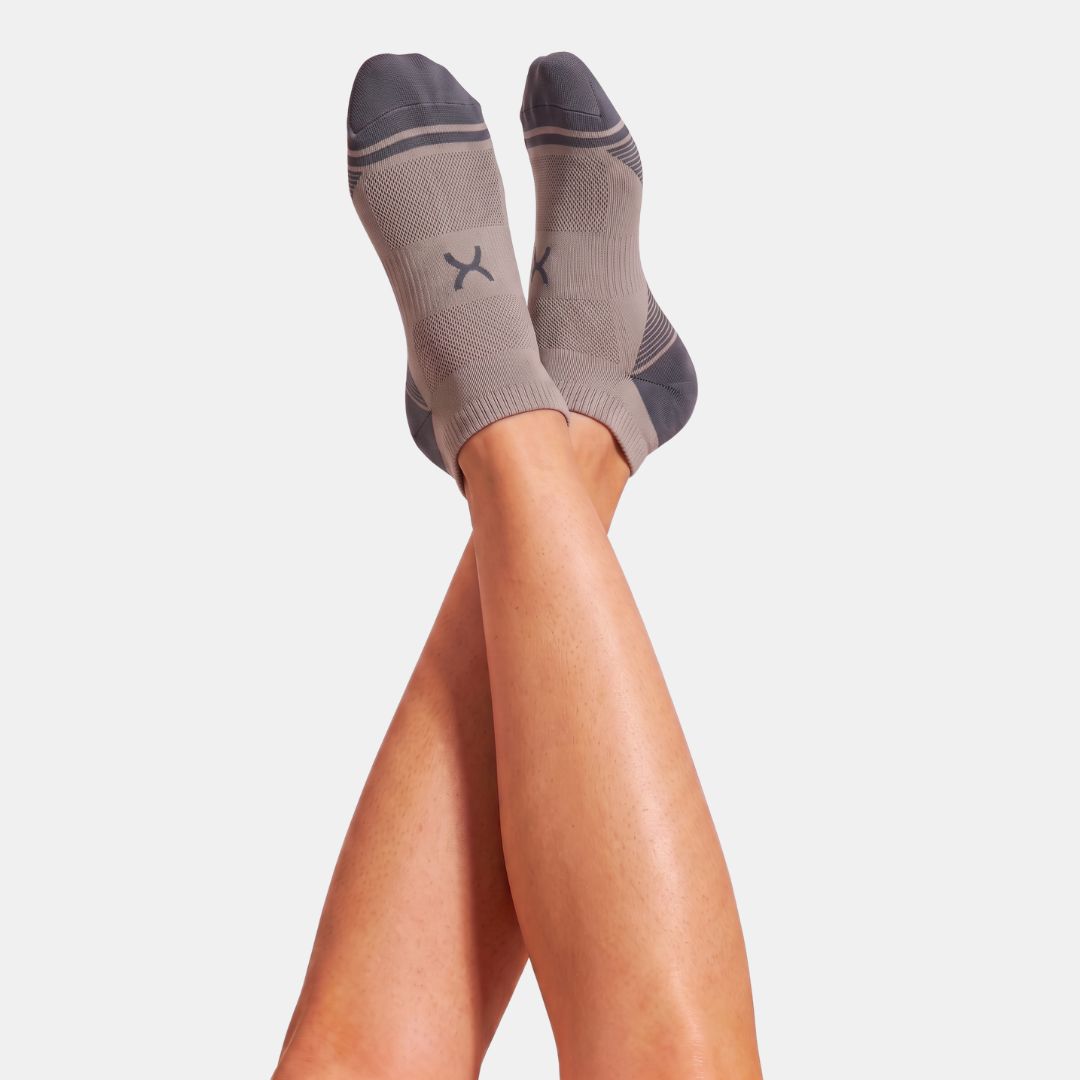 Gravel Power Stride Ankle Socks For Men in taupe and charcoal with mesh knit panels, shown on raised legs from below