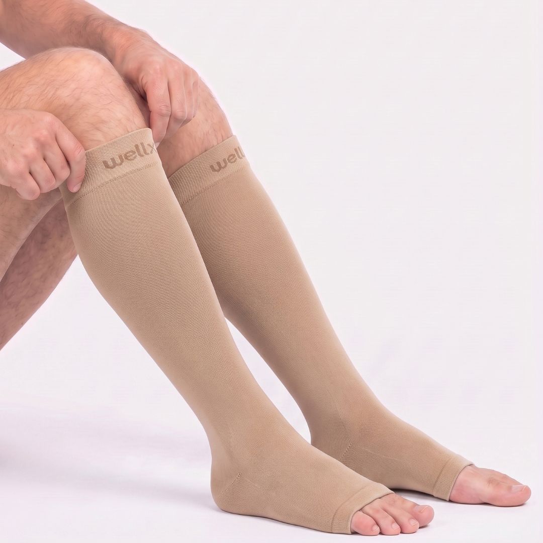 Gravel Toeless Compression Socks For Men A person wearing beige open-toe compression calf sleeves, shown from the knees down against a clean white studio background. The brand name 'well.