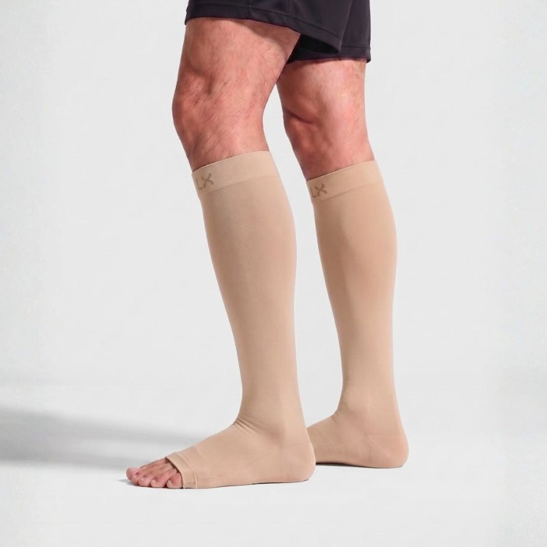 Gravel Toeless Compression Socks For Men Beige knee-high compression socks worn on a person's legs, shown from the mid-thigh down against a clean light gray studio background.