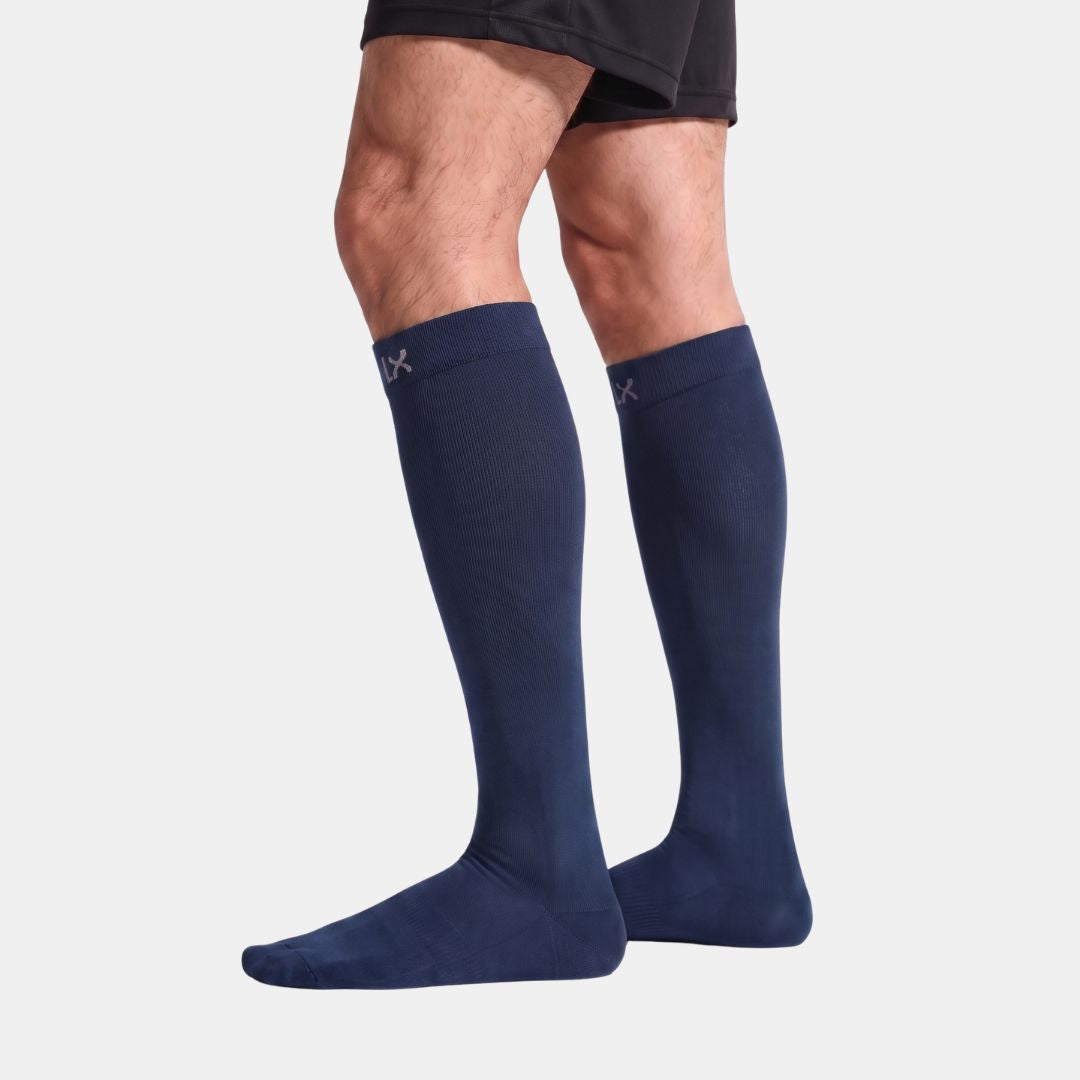 Close-up of a person wearing Compression Socks For Men in Navy, low-cut athletic style, showing the legs and feet against a clean white studio background.