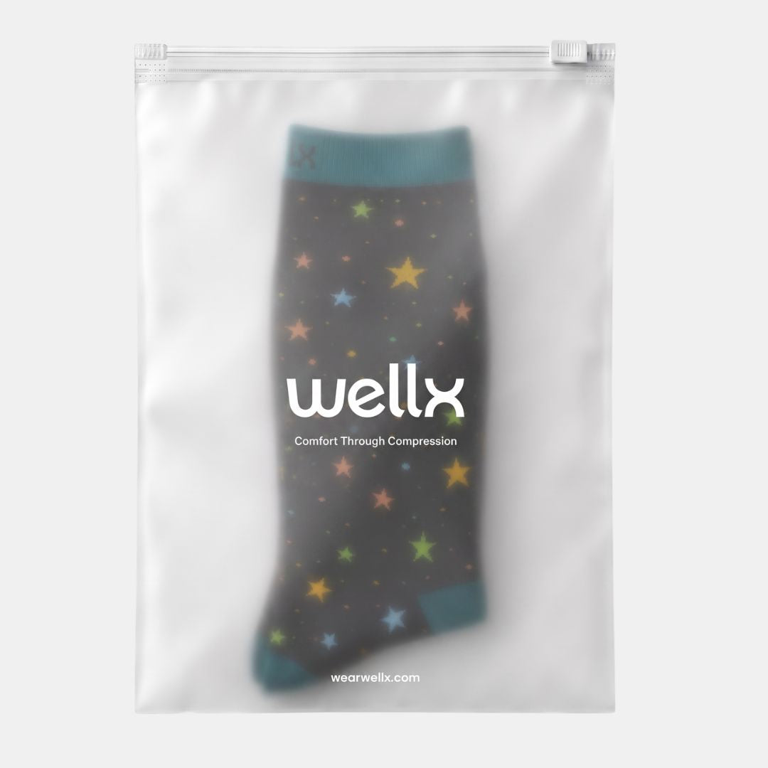 Stars Black/Green Compression Socks for Men, A gray compression sock inside a clear, resealable plastic pouch with white branding text that reads 'wellx' and 'Comfort Through Compression'.